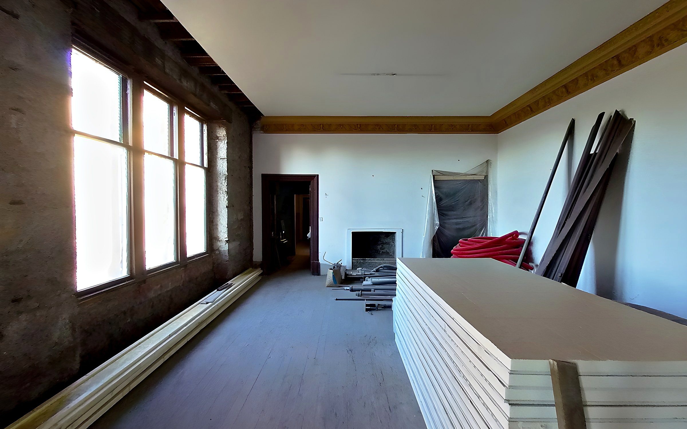 The dining room in January 2021: bare stone walls under the garden windows and boards stacked on the floor