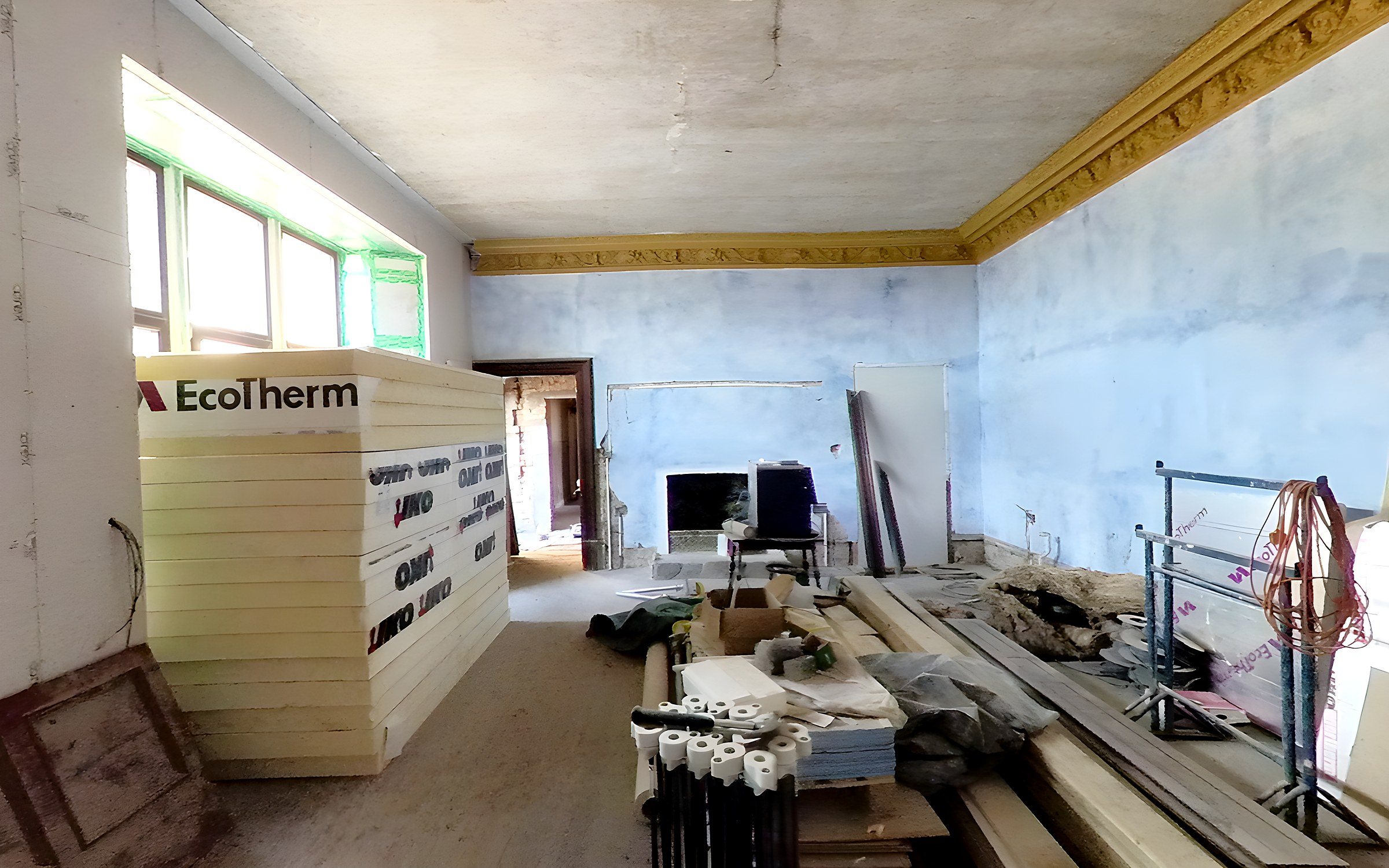 The same dining room in April 2022: walls plastered, gold cornice up and insulation boards stacked by the window