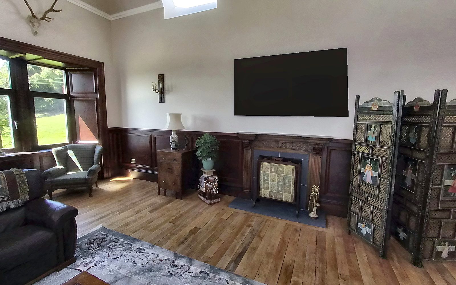 Still from a 360 tour: a finished lounge with panelling, fireplace and bay window