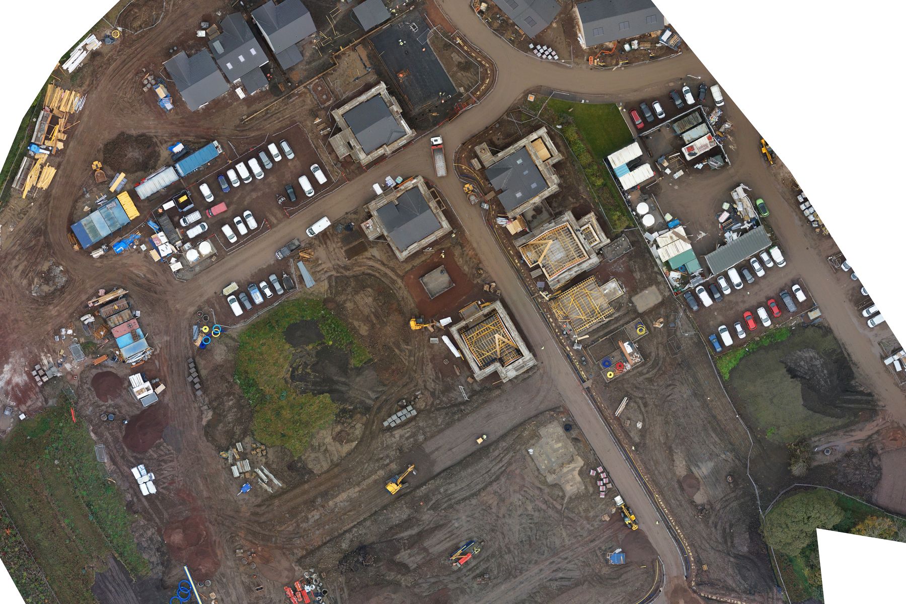 Straight-down drone map of a housing development, with every plot coloured by build stage, the site compounds marked and the British National Grid drawn over it