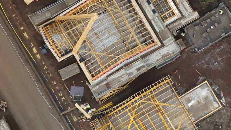 Close-up from the same map showing roof trusses on new houses and workers on the scaffold