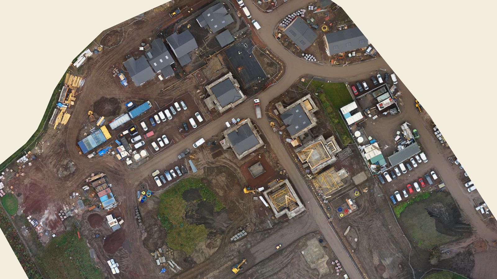 Straight-down drone map of a housing development, with finished houses, timber frames going up, site compounds and parked cars