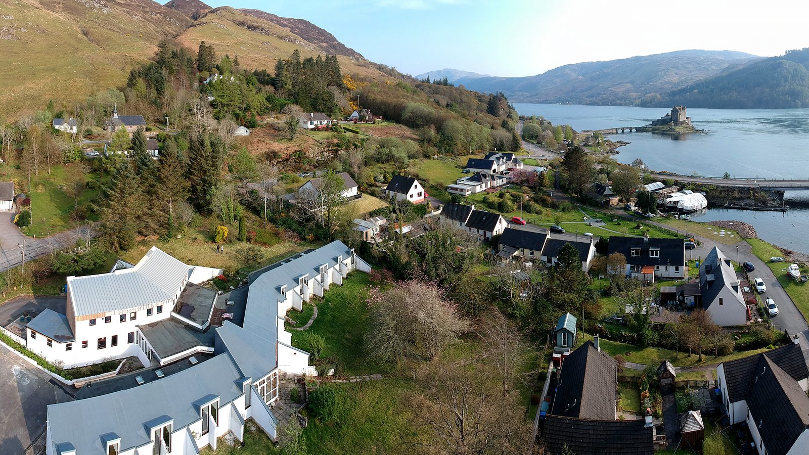 Aerial view over a Highland village and sea loch, with a castle on its island